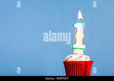 Nummer 1 Geburtstag Kerze in eine Cupcake vor einem blauen Hintergrund Stockfoto