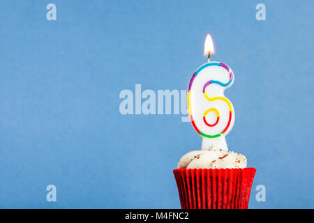 Nummer 6 Geburtstag Kerze in eine Cupcake vor einem blauen Hintergrund Stockfoto