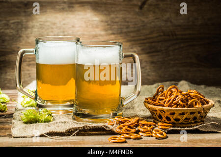 Zwei Gläser Bier Schaum mit Hop und Brezeln auf hölzernen Tisch Stockfoto