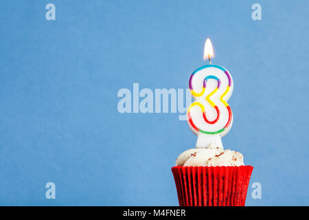 Nummer 3 Geburtstag Kerze in eine Cupcake vor einem blauen Hintergrund Stockfoto