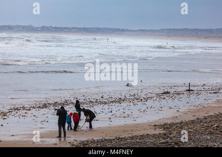 Eine Familie, die zusammen auf Blyth Strand, der Mann nimmt Fotos, raue Nordsee im Winter, Northumberland, Großbritannien Stockfoto