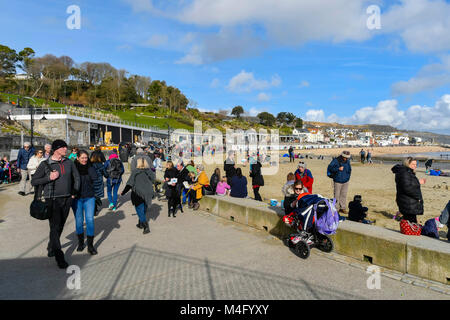 Lyme Regis, Dorset, Großbritannien. 16. Februar 2018. UK Wetter. Urlauber und Besucher an der Strandpromenade genießen Sie den blauen Himmel und warmen Winter Sonnenschein in den Badeort Lyme Regis in Dorset während der Herbstferien Urlaub. Foto: Graham Jagd-/Alamy Leben Nachrichten. Stockfoto