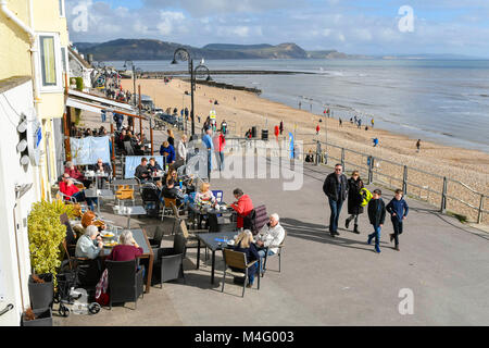 Lyme Regis, Dorset, Großbritannien. 16. Februar 2018. UK Wetter. Urlauber und Besucher an der Strandpromenade genießen Sie den blauen Himmel und warmen Winter Sonnenschein in den Badeort Lyme Regis in Dorset während der Herbstferien Urlaub. Foto: Graham Jagd-/Alamy Leben Nachrichten. Stockfoto