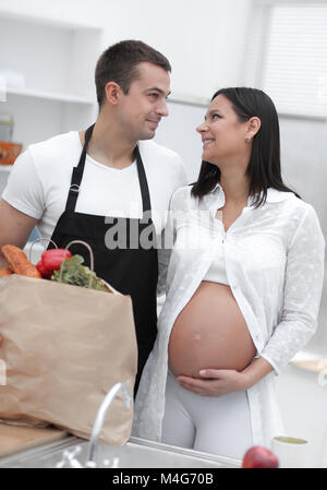 Mann und seine schwangere Frau sind Kämmen durch die Pack, stehen in der Küche Stockfoto