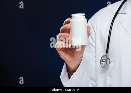 Schließen upof männlicher Arzt in Uniform mit Stethoskop, Flasche mit Pillen über dunklen Hintergrund gekleidet Stockfoto