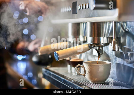 Barista, einen Espresso mit einem klassischen italienischen Kaffee Maschine mit Dampf im Hintergrund. Stockfoto