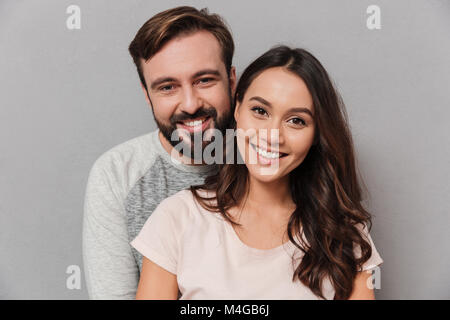 Close up Portrait von ein glückliches junges Paar umarmen und Kamera über grauer Hintergrund Stockfoto