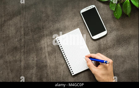 Modernes, sauberes Leder Desktop Office Tabelle mit männlichen Hand schreiben. Stockfoto