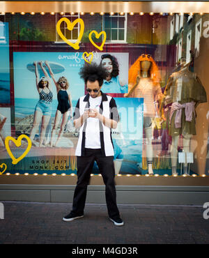 Farbe Foto von einem jungen Mann auf seinem Mobiltelefon, Carnaby Street, London, England, UK. Credit: London Snapper Stockfoto