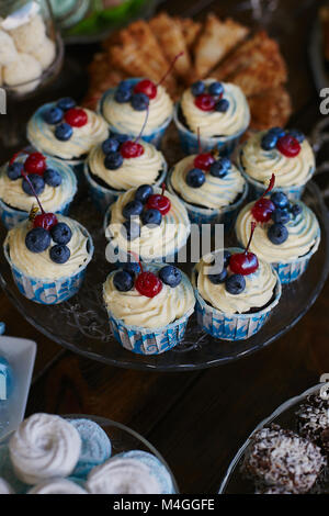 Cupcakes mit Schlagsahne, Kirsche, Heidelbeere - Candy Bar eingerichtet, leckeres Buffet Stockfoto