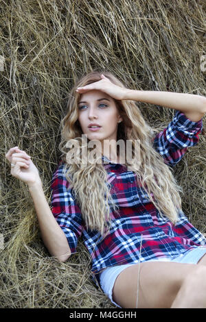 Junge blonde Landmädchen in der Nähe von Heuhaufen Stockfoto