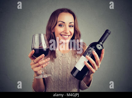 Junge Frau mit einem Glas Wein und Flasche glücklich an Kamera genießen Geschmack suchen. Stockfoto