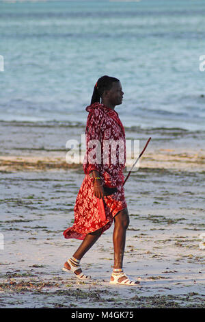 Maasai Mann zu Fuß am Strand bei Sonnenuntergang, Kiwengwa Beach, Sansibar, Tansania Stockfoto