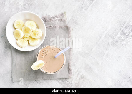 Banane Milchshake in Glas und Stein mit kopieren. Gesundes Getränk. Vegetarier, Veganer trinken. Ansicht von oben, flach Stockfoto