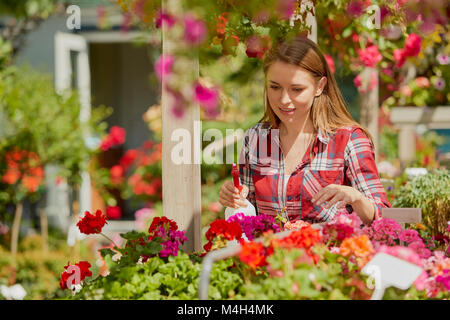 Frau Sprühwasser auf Blumen Stockfoto