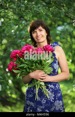 Die durchschnittliche Frau mit Blumen in einem Garten Stockfoto