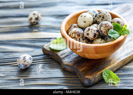 Kleine gesprenkelten Eiern in eine hölzerne Schüssel. Stockfoto