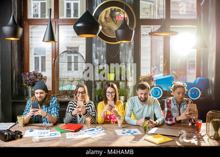 Freunde sitzen mit Telefon im Cafe Stockfoto