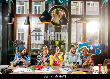 Freunde sitzen mit Telefon im Cafe Stockfoto