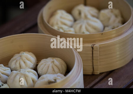 Chinesische Knödel (baozi) in einem traditionellen Holz- Bambus Warenkorb Dampfgaren Stockfoto