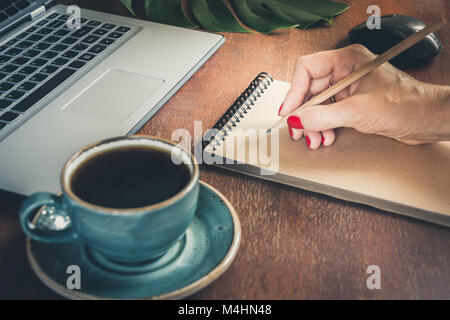 Weibliche Hände schreiben auf Notebook im Coffee Shop. Schreiben Konzept Stockfoto