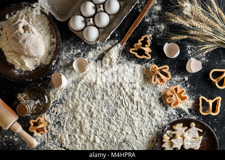 Der Prozess, in dem Cookie. Kochen Teig für Cookies, Butter, Eier, Kochgeräte, Mehl auf einem Schwarzen Tisch. Ansicht von oben mit der Kopie Raum, Mockup für Stockfoto