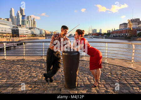 Ein junges Paar in Puerto Madero bei Sonnenuntergang, mit der "Puente de la Mujer" im Hintergrund. Buenos Aires, Argentinien. Stockfoto