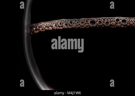 Rotwein mit Blasen auf der Oberfläche in Gläsern auf schwarzem Hintergrund leer Stockfoto