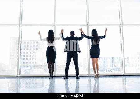 Business Team erhobenen Händen im Büro zufrieden mit Ergebnis, Gruppe der Gewinner feiern Sieg oder großen Erfolg gegen Windows Stockfoto