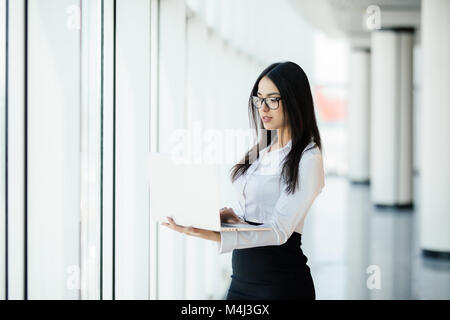 Young Business Frau arbeitet sie in ihrem luxuriösen Amt, ein Laptop gegen Panoramafenster mit Blick auf das Geschäft Stockfoto