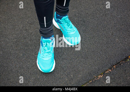 Die Beine der Frau in blau gefärbten Laufschuhe auf Asphalt. Stockfoto