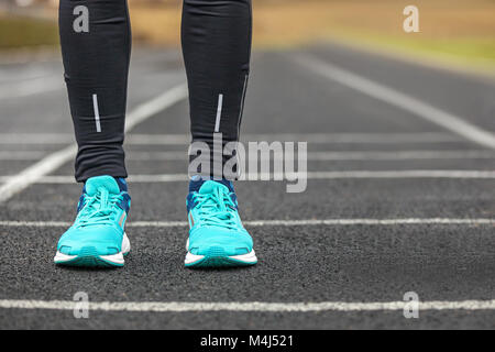Die Beine der Frau in blau gefärbten Laufschuhe auf Asphalt. Stockfoto