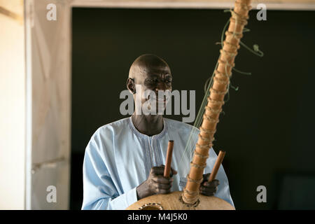 Eine ethnische Mandinka tribesman spielt die Kora, ein traditionelles Musikinstrument, in Jufureh, Gambia, Westafrika. Stockfoto