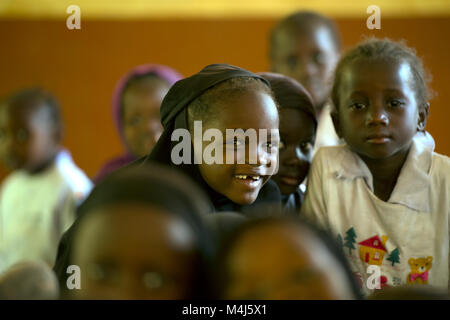 Eine junge mandinka Stamm Schülerin von ihren Mitschülern an einer Dorfschule in Gambia, Westafrika umgeben. Stockfoto