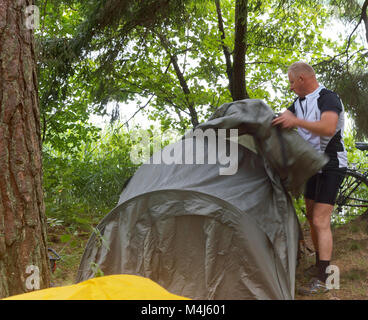 Ein Mann löst eine touristische Hütte im Wald, ein Mann legt eine touristische Hütte Stockfoto