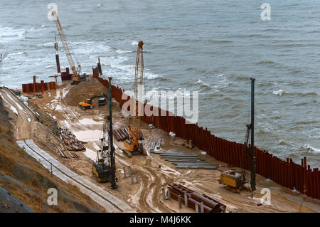 Bau der Promenade am Meer, Stärkung der Küste, spezielle Ausrüstung am Strand Stockfoto