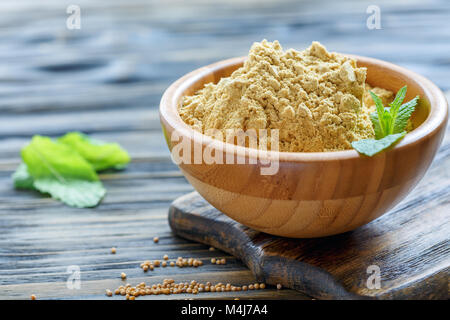 Senfpulver in eine hölzerne Schüssel. Stockfoto