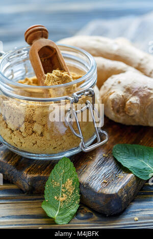 Gemahlener Ingwer in einem Glas und frische Ingwerwurzel. Stockfoto