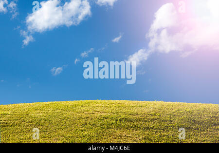 Grüne Rasen oder Wiese mit blauem Himmel und Sonne flare Stockfoto