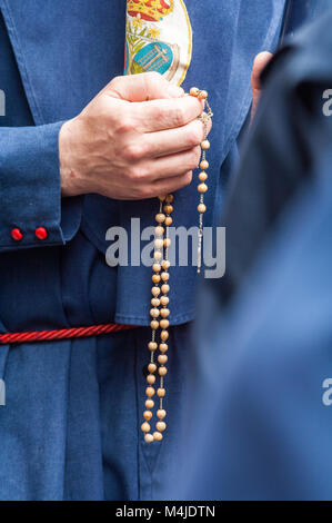 Detail der Hand des Pönitenten der Bruderschaft des "El Baratillo' mit einem Rosenkranz, zählen die Perlen beim Beten. Stockfoto