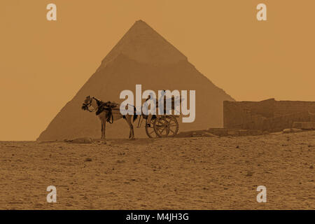 Ein Pferd und Wagen das der Großen Pyramide von Gizeh oder der Pyramide des Cheops, Pyramiden, Giza, Ägypten, Nordafrika sepia Getont Stockfoto