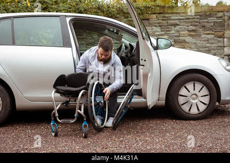 Behinderte Menschen im Rollstuhl halten und Aussteigen aus einem Auto Stockfoto