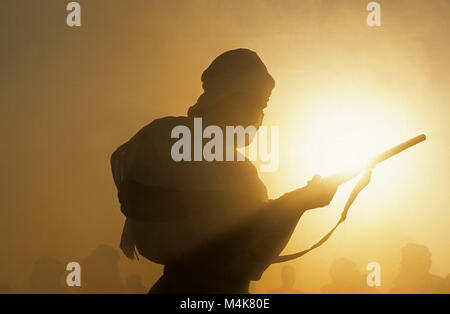 Algerien. Timimoun. Western Sand Meer. Grand Erg Occidental. Sahara. Mann laden Waffe während des Festivals. Stockfoto