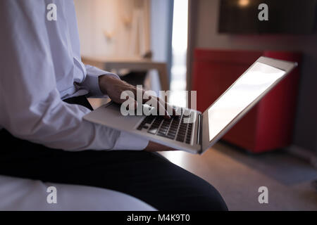 Geschäftsmann mit einem Laptop auf Bett Stockfoto