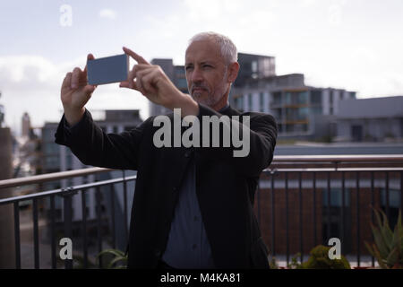 Geschäftsmann unter Bild auf Handy Stockfoto