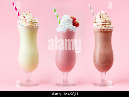 Erdbeere, Schokolade und Vanille Milchshake mit Schlagsahne auf rosa Hintergrund Stockfoto
