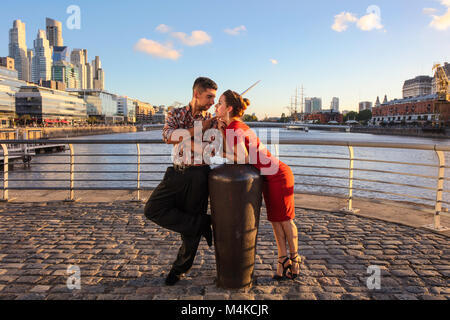 Ein junges Paar in Puerto Madero bei Sonnenuntergang, mit der "Puente de la Mujer" im Hintergrund. Buenos Aires, Argentinien. Stockfoto