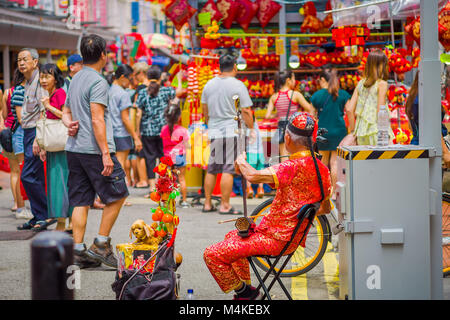 Singapur, Singapur - Februar 01, 2018: Elder Straßenmusiker Straßenmusik entlang einer befahrenen Straße während des chinesischen neuen Jahres in Singapur Stockfoto