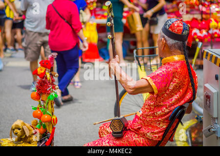 Singapur, Singapur - Februar 01, 2018: Elder Straßenmusiker Straßenmusik entlang einer befahrenen Straße während des chinesischen neuen Jahres in Singapur Stockfoto