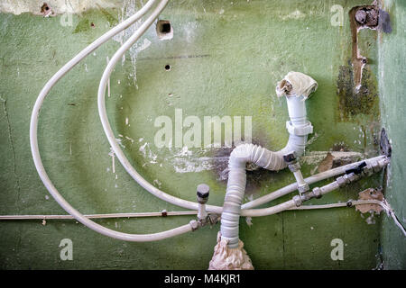 Wasser- und Abwasserleitungen auf dem Hintergrund der alten Mauer. Reparatur im Haus. Verbindung von Metall - Kunststoff Rohre Stockfoto
